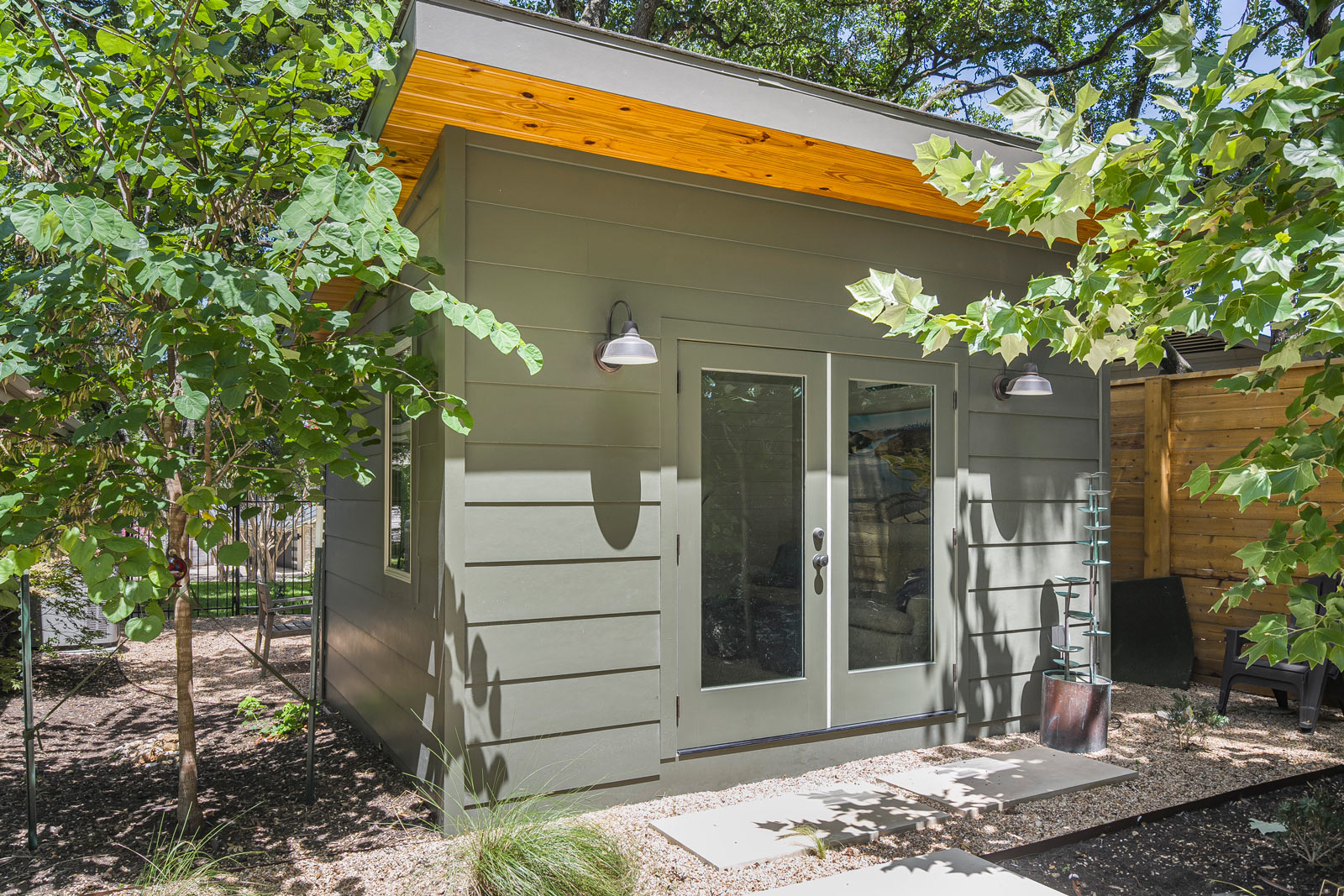 Sage green backyard gym structure with French doors and barn-style lighting